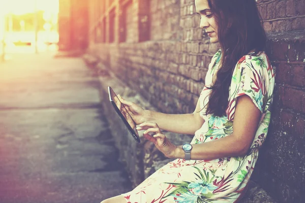 Girl holding digital tablet pc at street in sunrise light