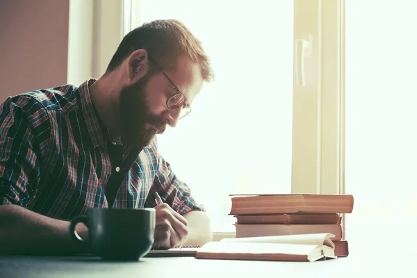 Bearded man writing with pen