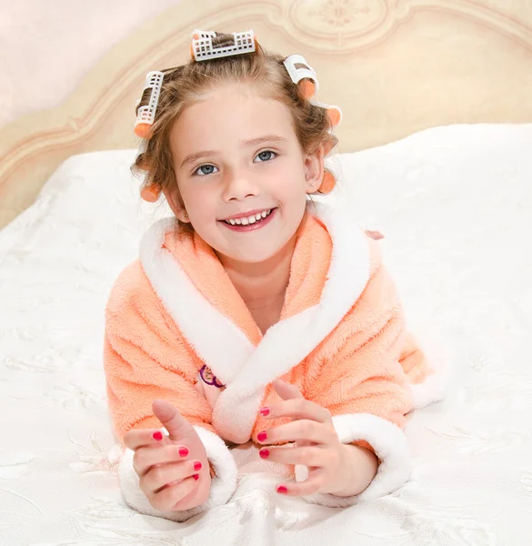 Happy funny little girl with manicure and hair curlers