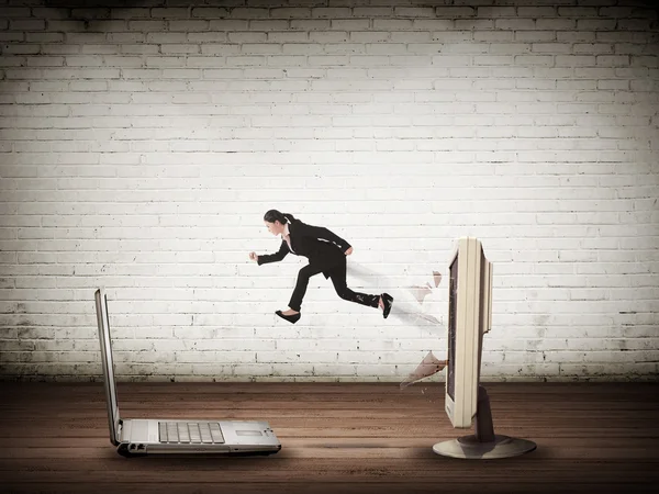 Business woman jumping from desktop computer to laptop