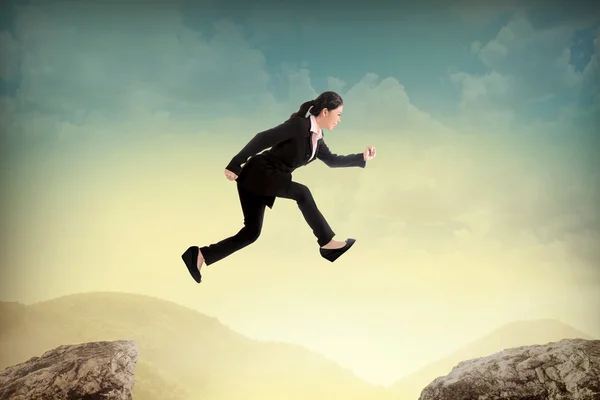 Business woman jump to another peak of mountain