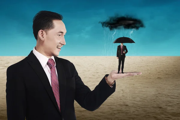 Business man holding small man using umbrella