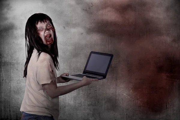 Creepy female zombie typing with laptop