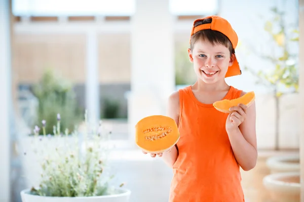 Cute little boy holding sliced orange cantaloupe melon in hands