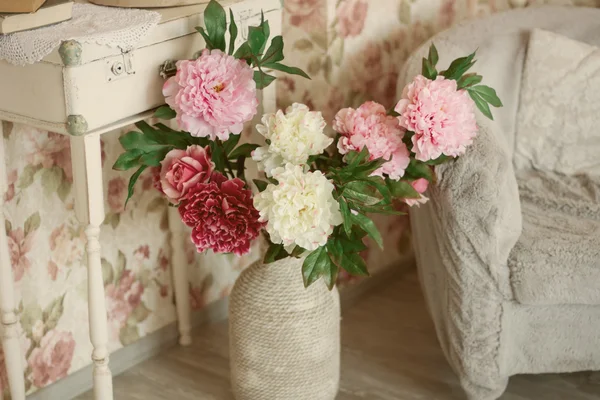 Artificial flowers in a decorative vase standing on the floor in