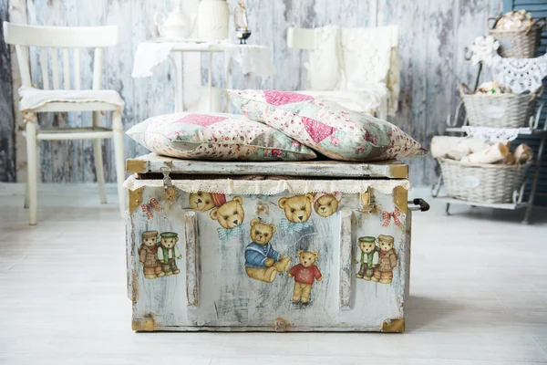 Old chest for toys with painted bears and pillows are.