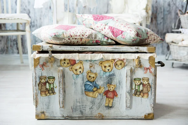 Old chest for toys with painted bears and pillows are