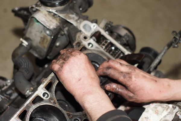 Mechanic hands tighten nut with wrench while repairing engine