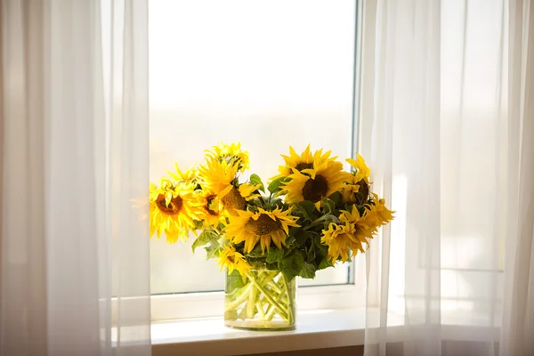 Bouquet of sunflowers in a vase on the window.