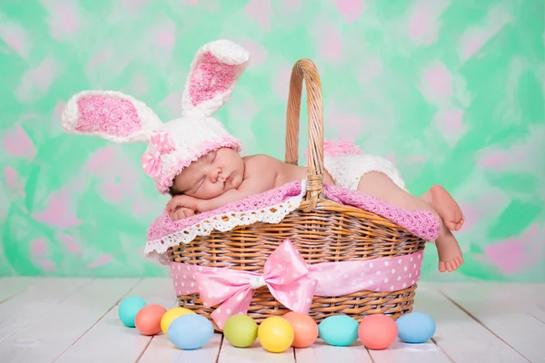 Newborn baby girl in a rabbit costume has sweet dreams on the wicker basket. Easter Holiday