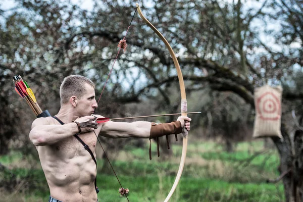 Archery. A young man aiming a bow at a target