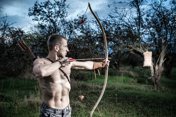 Archery. A young man aiming a bow at a target