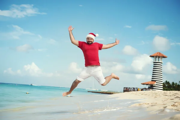 Santa Claus and wish a happy new year. Funny Grandfather Frost jumps on the sea. Tropical sandy beach - xmas travel vacation discounts and travel agencies price reductions concept