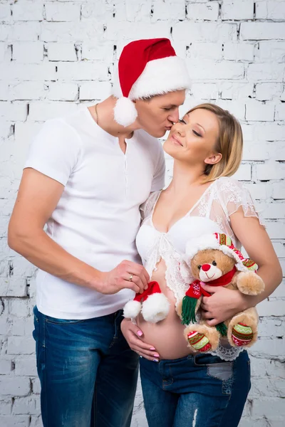 Young pregnant family. Husband kisses his wife. Concept New Year and happy pregnancy.