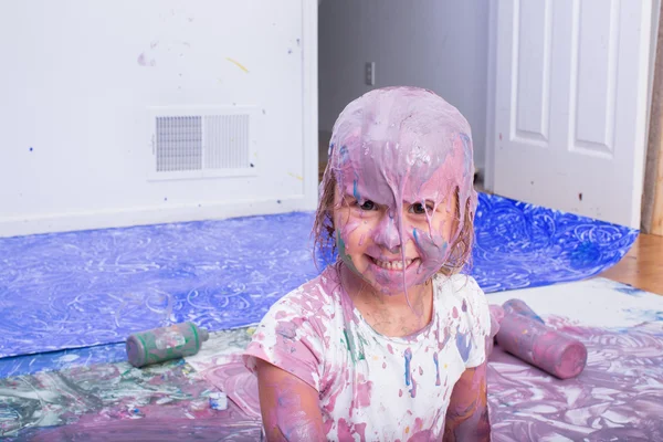 Smiling girl covered in various colors of paint