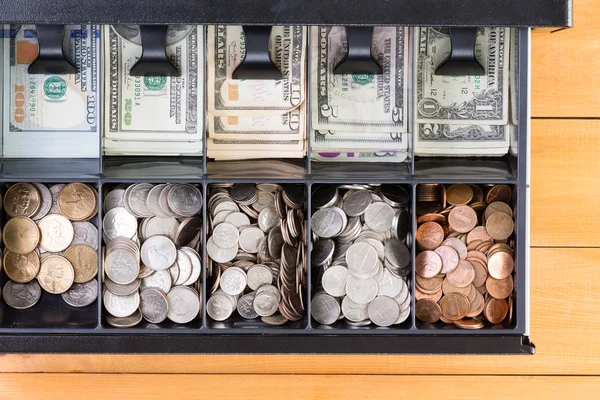 Open cash register drawer on wooden table