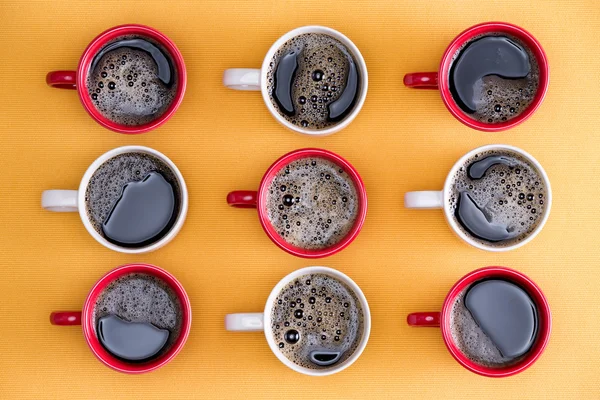 Mugs of black coffee in alternating colors
