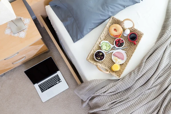 Laptop on Floor Beside Bed with Breakfast Tray