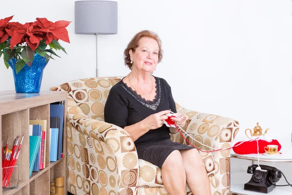 Elderly lady sitting in an armchair knitting