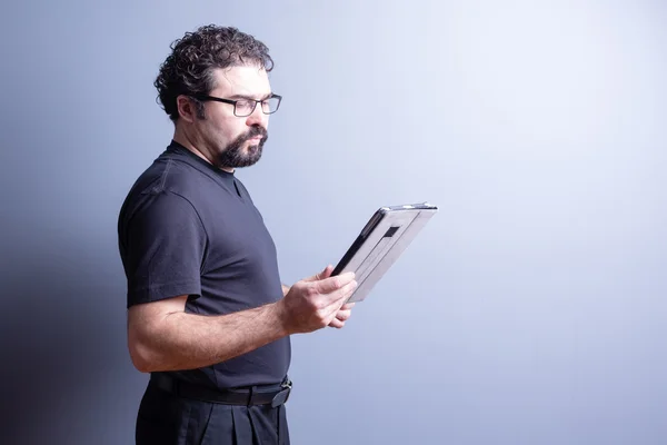 Man with Beard and Glasses Reading from Tablet