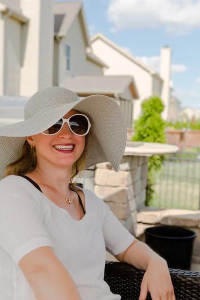 Woman in Hat and Sunglasses Sitting on Patio