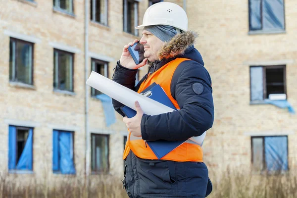 Building inspector talking on smartphone near the building