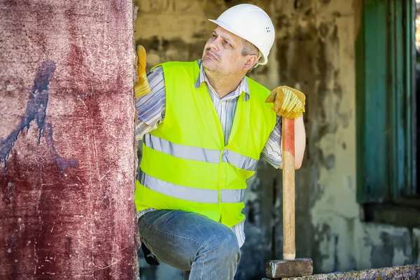 Construction worker with sledgehammer near wall
