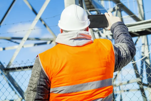 Engineer filmed with tablet PC at outdoors near metal structures