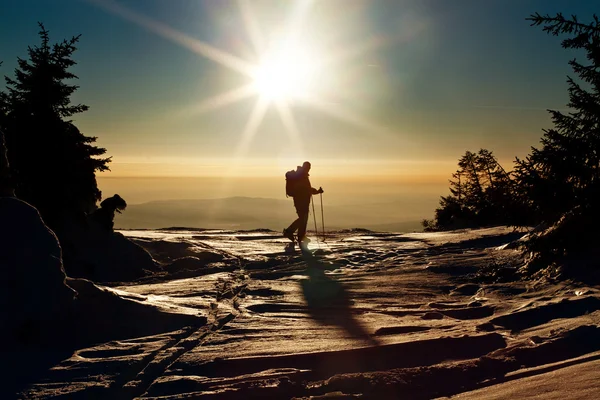 Backcountry skier reaching the summit at sunset