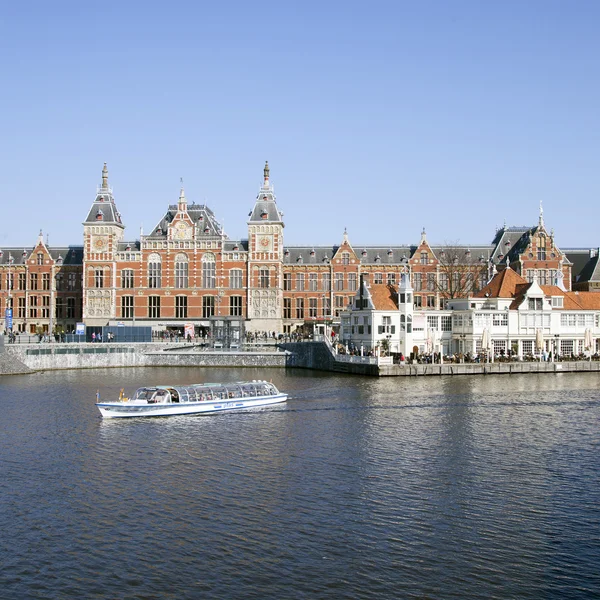 Canal cruise boat in front of amsterdam central railway station
