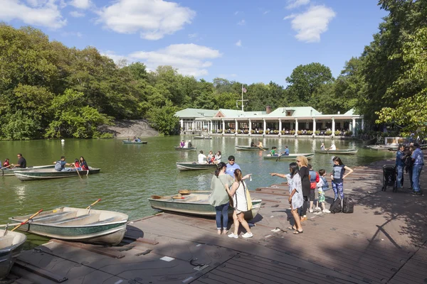 People row in boats on new york city central park pond near boat