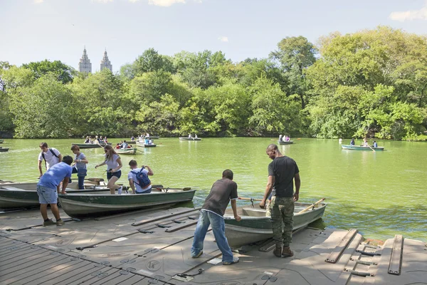 People row in boats on new york city central park pond near boat
