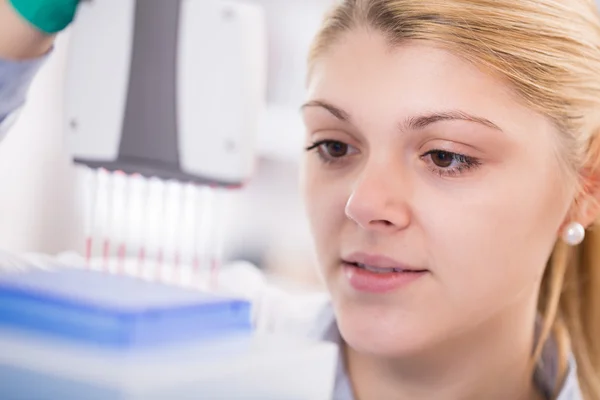 Women science pipetting solution into the glass test tube