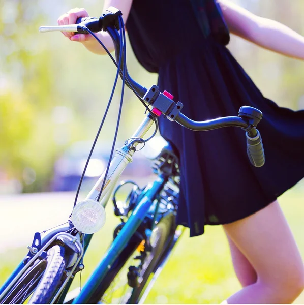 Girl in color short black stands near bike