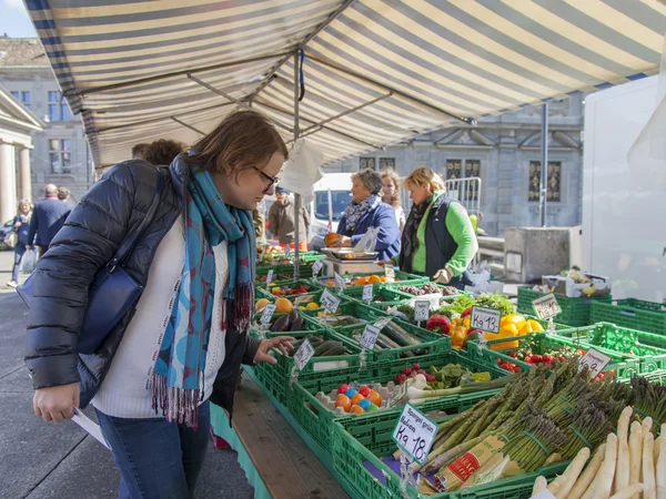 ZURICH, SWITZERLAND, on MARCH 26, 2016. Spring morning. Buyers and sellers near counters with vegetables and fruit in the market