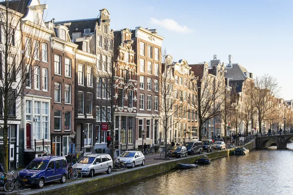 AMSTERDAM, NETHERLANDS on MARCH 28, 2016. Typical urban view in the spring afternoon. The channel and buildings of the XVII-XVIII construction on embankments. The walking ship floats on the channel