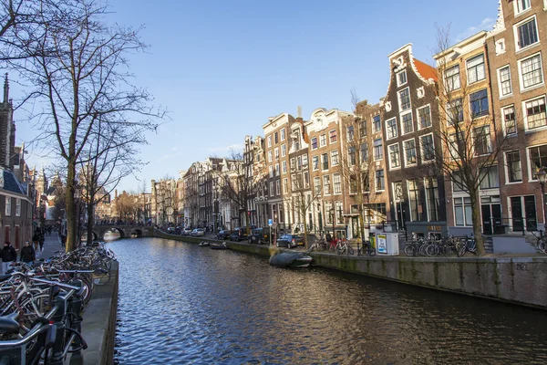 AMSTERDAM, NETHERLANDS on MARCH 28, 2016. Typical urban view in the spring afternoon. The channel and buildings of the XVII-XVIII construction on embankments. The walking ship floats on the channel