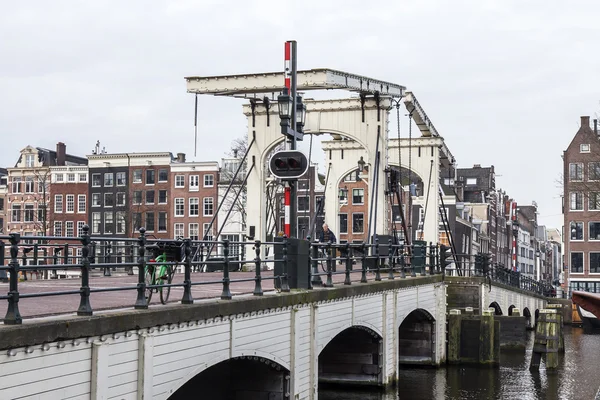 AMSTERDAM, NETHERLANDS on MARCH 31, 2016. Typical urban view in the spring. An old movable bridge through the canal and buildings of the XVII-XVIII construction on embankments