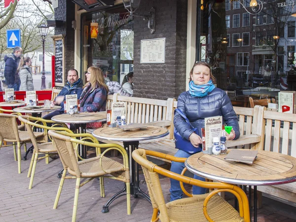 AMSTERDAM, NETHERLANDS on MARCH 31, 2016. Typical urban view in the spring morning. Little tables of summer cafe under the open sky
