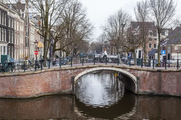 AMSTERDAM, NETHERLANDS on MARCH 31, 2016. Typical urban view. Obridge via the channel. The channel and buildings of the XVII-XVIII construction on embankments.