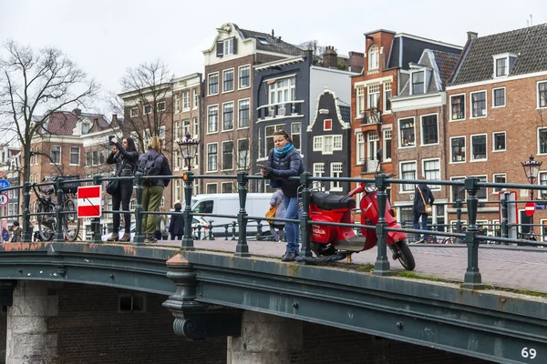 AMSTERDAM, NETHERLANDS on MARCH 31, 2016. Typical urban view. Obridge via the channel. The channel and buildings of the XVII-XVIII construction on embankments.