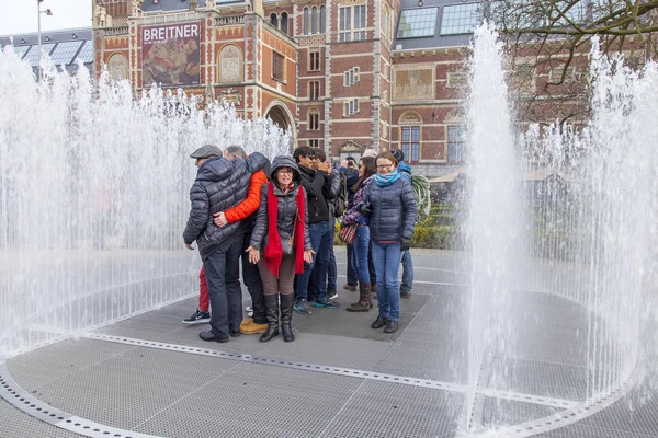 AMSTERDAM, NETHERLANDS on MARCH 31, 2016. Urban view. The fountain on the museum square. Tourists have a good time.