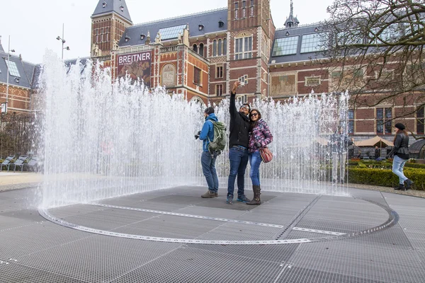 AMSTERDAM, NETHERLANDS on MARCH 31, 2016. Urban view. The fountain on the museum square. Tourists have a good time.