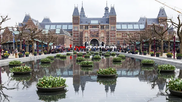 AMSTERDAM, NETHERLANDS on MARCH 31, 2016. Museum Square. Rijksmuseum. Tourists have a good time near the inscription I AMsterdam. The fountain decorated by flowerpots with tulips