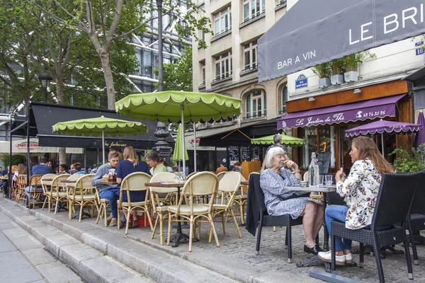 PARIS, FRANCE, on JULY 5, 2016. Typical Parisian street in the morning. People have a rest and eat in cafe under the open sky.