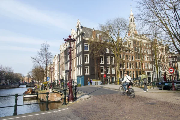 AMSTERDAM, NETHERLANDS on MARCH 31, 2016. Typical urban view. The channel and buildings of the XVII-XVIII construction on embankments. the old bridge via the channel.