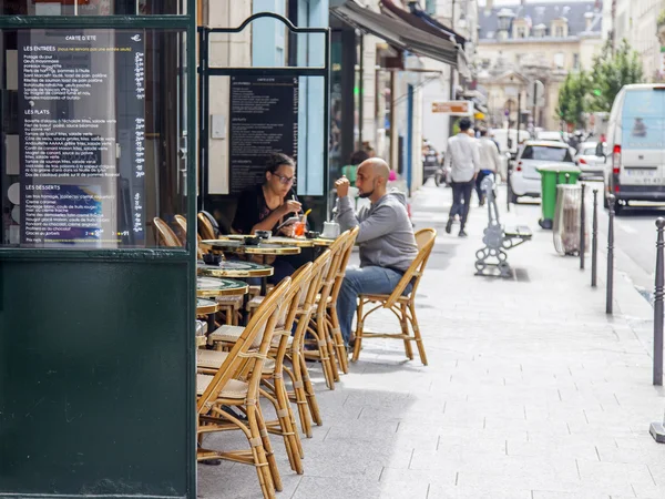 PARIS, FRANCE, on JULY 7, 2016. Typical Parisian street in the morning. People eat and have a rest in cafe under the open sky.
