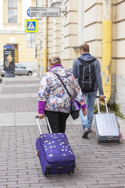 ST. PETERSBURG, RUSSIA, on August 21, 2016. Urban view. Tourists with suitcases go down the street