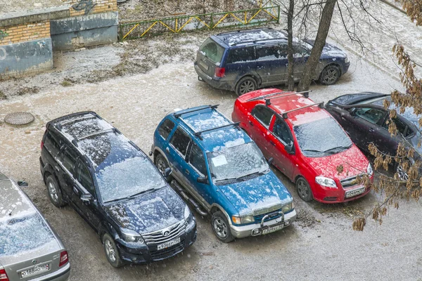 Pushkino, Russia, on November 17, 2014. The first snow in the city. Cars stand on a parking in the inhabited massif