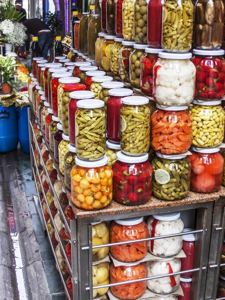 Glass jars with a tinned pickles and marinades on a counter of the market